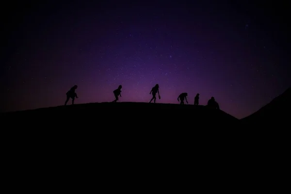 Beautiful shot of silhouettes of people walking on a dark ground and stars on a purple background