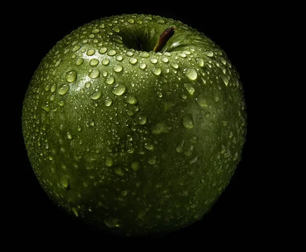 Closeup shot of a fresh green apple covered with water drops isolated on a black background — Stock Photo, Image