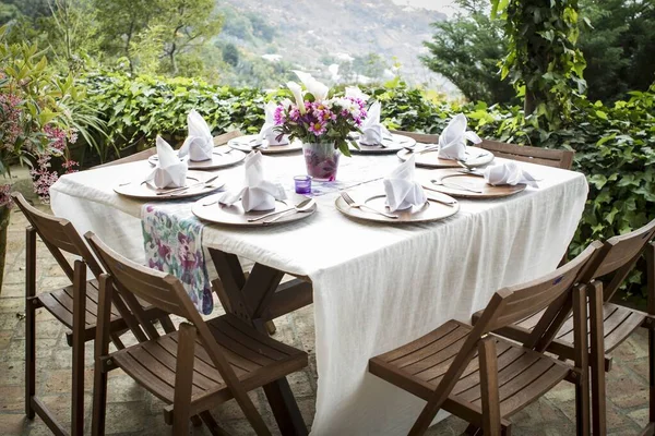 Tafel vol borden en een bloemvaas op een prachtig balkon met een prachtig uitzicht — Stockfoto