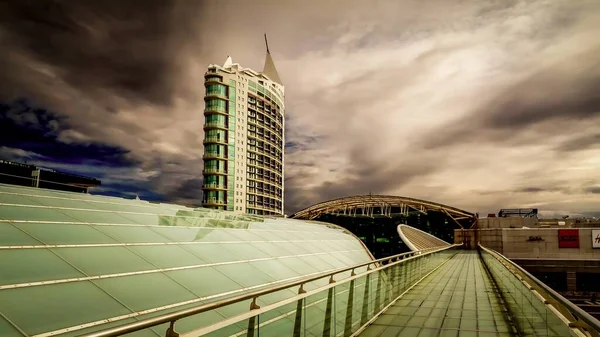 Hermosa foto de un moderno edificio comercial con paredes de vidrio verde bajo el cielo nublado — Foto de Stock