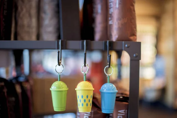 Close-up shot van drie koele kleurrijke snuisterijen met de vorm van koffiebeker opgehangen aan een ijzeren hanger — Stockfoto