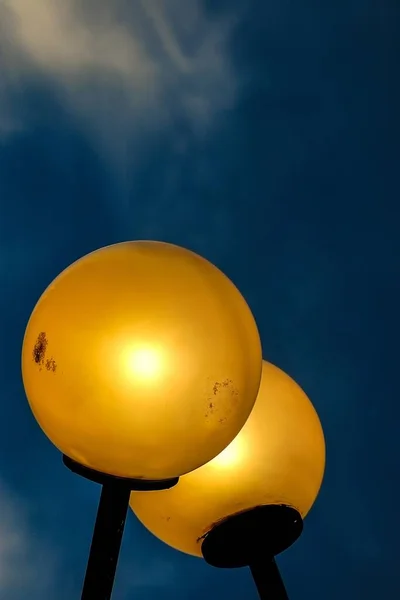 Vertical tiro de ângulo baixo de luzes de rua amarelas sob o belo céu azul — Fotografia de Stock