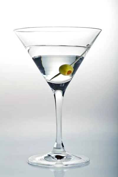 Вертикальный снимок бокала мартини и оливки на белом фоне — стоковое фото