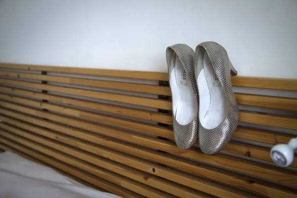 Par de tacones altos en una cabecera de cama de madera en una habitación blanca —  Fotos de Stock