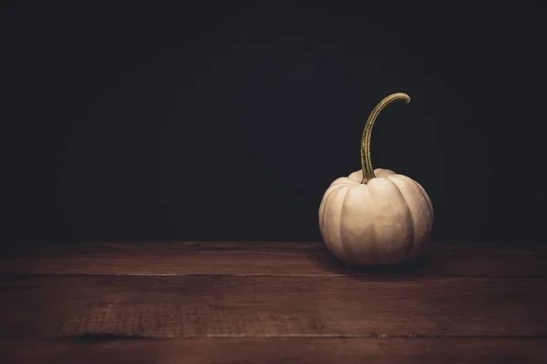 Abóbora branca em uma superfície de madeira com um fundo preto - Conceito de Halloween — Fotografia de Stock