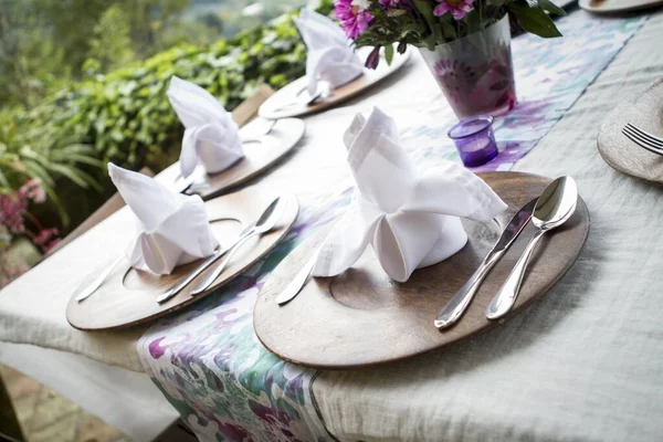 Assiettes en bois avec de beaux mouchoirs sur une table dans un jardin — Photo