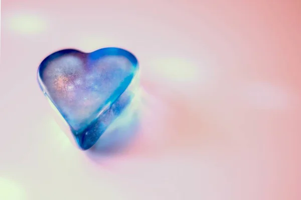 Closeup shot of a blue crystal heart pebble on a pink surface — Stock Photo, Image