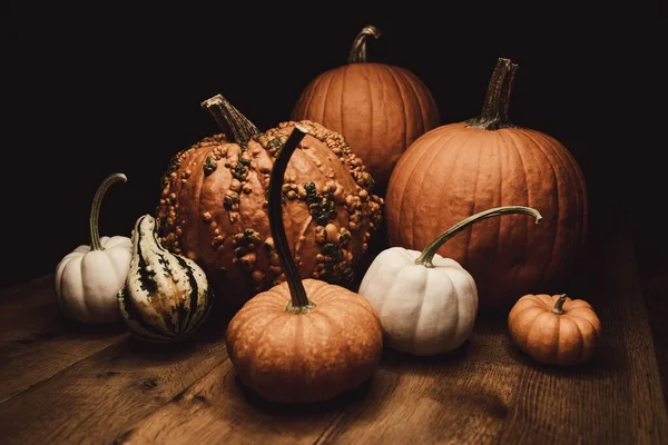 Abóboras e abóboras em uma superfície de madeira com um fundo preto - Conceito de Halloween — Fotografia de Stock
