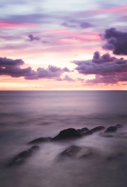 Tiro vertical de uma vista deslumbrante das nuvens no céu colorido ao longo do horizonte — Fotografia de Stock