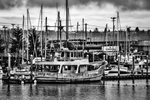 Gray scale shot of boats on the sea near the dock with the cloudy sky in the background — ストック写真