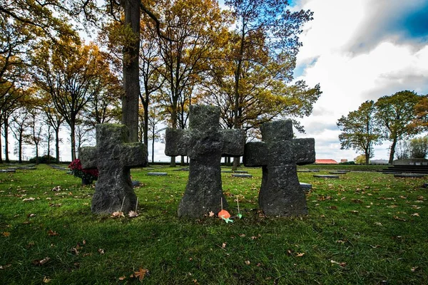 在阴云密布的天空下 是一个有石雕和秋天叶子的树的坟场 — 图库照片