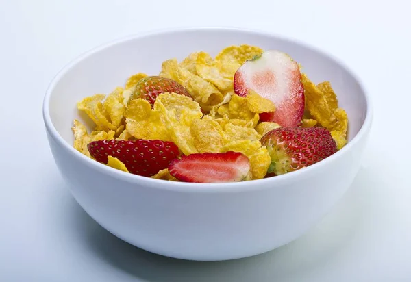 Closeup shot of a white bowl full of cereal and strawberries on a white background — Stock Photo, Image