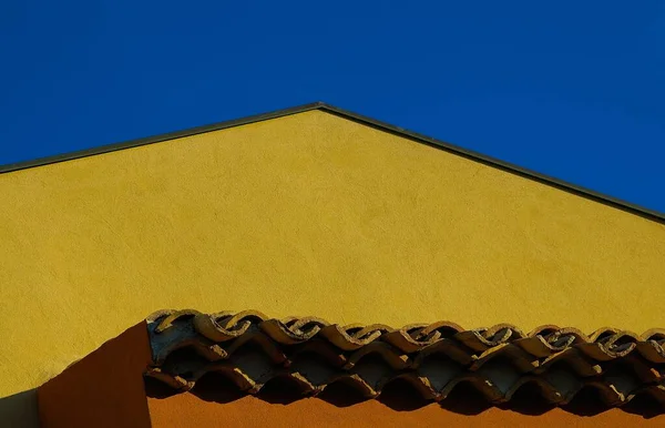 Bajo ángulo de tiro del techo de un edificio histórico amarillo bajo el cielo azul —  Fotos de Stock