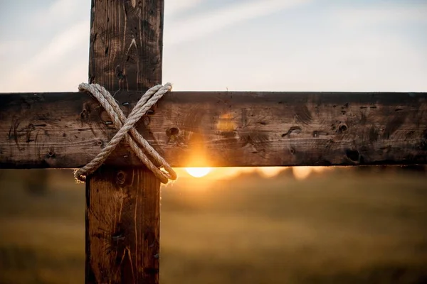 Primer plano de una cruz de madera con el sol en el fondo borroso —  Fotos de Stock