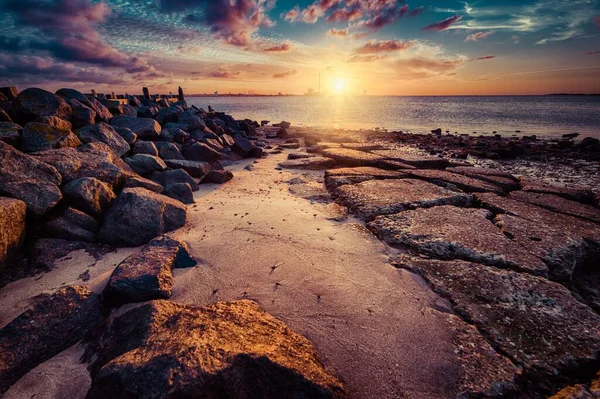 Hermosa puesta de sol en la playa cubierta de rocas de diferentes formas y tamaños — Foto de Stock