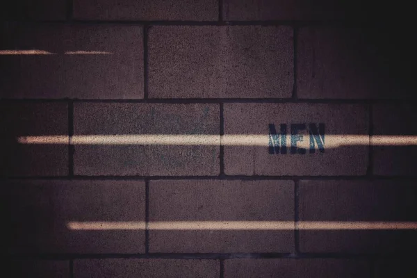 Imagem de fundo de uma parede de tijolo marrom com uma impressão MEN — Fotografia de Stock