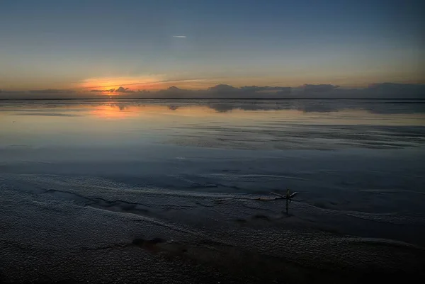 Wunderschöner Sonnenuntergang am Strand, der die perfekte Kulisse für Abendspaziergänge am Ufer schafft — Stockfoto