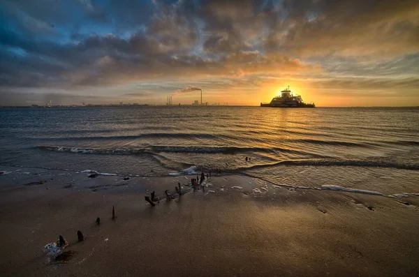 Loď plující nad mořem během úchvatného západu slunce pod zataženou oblohou — Stock fotografie