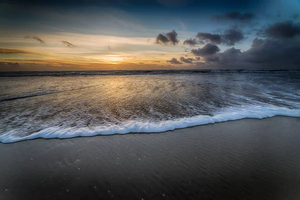 Sahilde güzel bir gün batımı sahilde akşam yürüyüşü için mükemmel bir manzara yaratıyor. — Stok fotoğraf