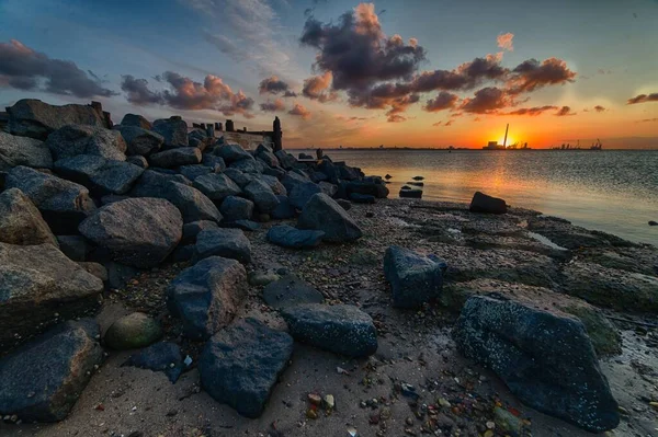 Belo pôr do sol na praia coberto de rochas de diferentes formas e tamanhos — Fotografia de Stock