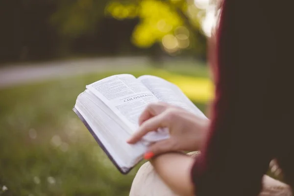 Primer plano de una mujer sentada mientras lee la Biblia con un fondo borroso — Foto de Stock