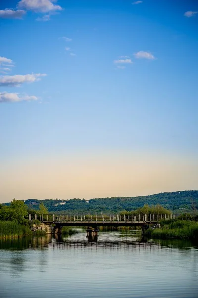 Vertical shot of a beautiful bridge in a lake and the bright calm sky in the background — Stok fotoğraf