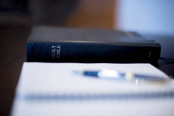 Επιλεκτική φωτογραφία εστίασης της Αγίας Γραφής σε ξύλινο τραπέζι με θολή φόντο — Φωτογραφία Αρχείου