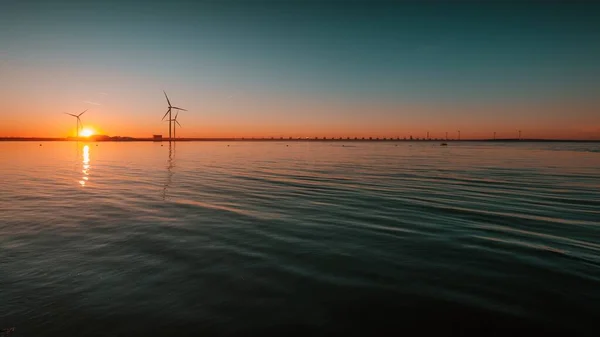 在迷人的落日的映衬下，平静的大海上，有着涡轮机的美丽景色 — 图库照片