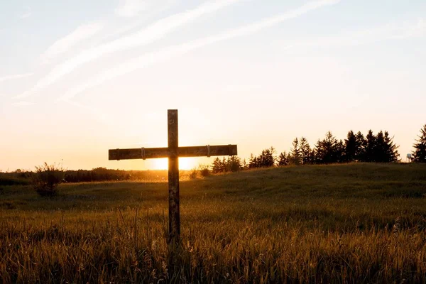Όμορφη βολή ενός ξύλινου σταυρού σε ένα χλοερό πεδίο με συννεφιασμένο ουρανό στο παρασκήνιο — Φωτογραφία Αρχείου