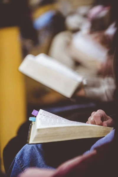 İncili okurken yan yana oturan kişinin dikey yakın çekimi bulanık arkaplanlı — Stok fotoğraf