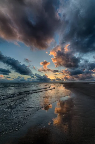Vertikale Aufnahme eines wunderschönen Sonnenuntergangs, der sich im Ozean spiegelt und die perfekte Kulisse schafft — Stockfoto