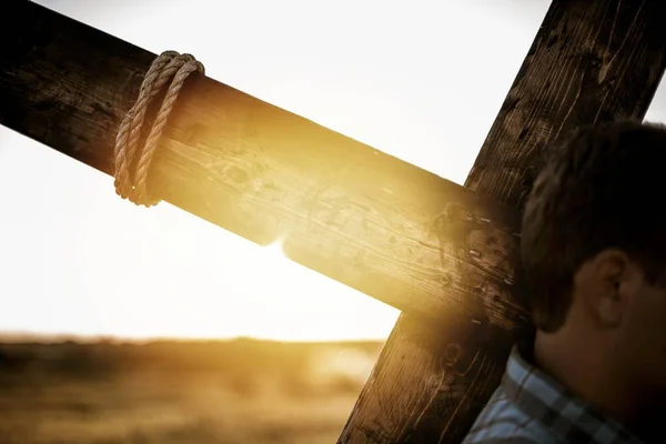 特写镜头 一个男人背着木制十字架 背后闪烁着阳光的特写镜头 — 图库照片