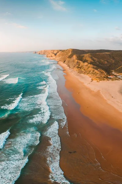 Plan vertical des vagues océaniques à couper le souffle et de la plage avec falaise rocheuse sous le ciel bleu — Photo