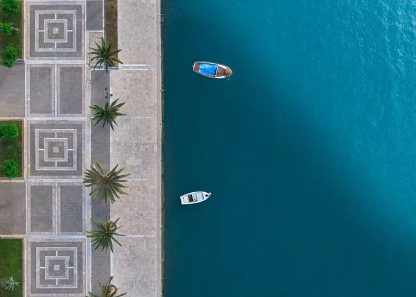 Hoge hoek schot van de stenige kustlijn met palmen van de zuivere blauwe zee met twee kleine boten erin — Stockfoto