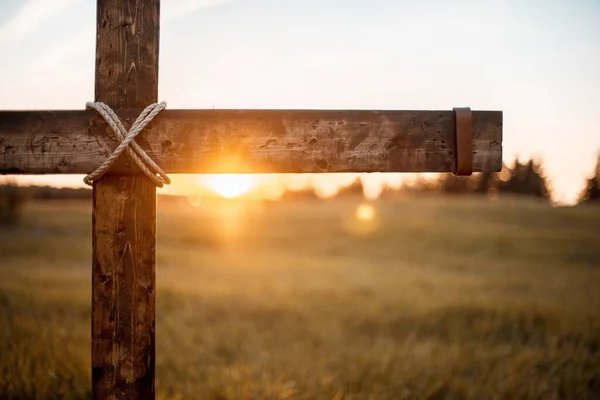 Primer plano de una cruz de madera con el sol brillando en el fondo borroso —  Fotos de Stock