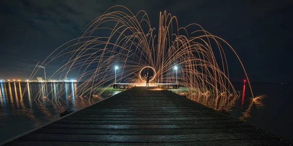 Belo tiro de um show de laser no cais sobre o mar durante a noite — Fotografia de Stock