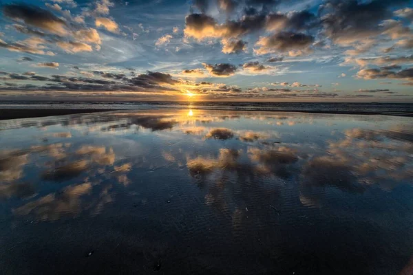 Wunderschöner Sonnenaufgang, der sich im Meer spiegelt und die perfekte Kulisse für Morgenspaziergänge schafft — Stockfoto