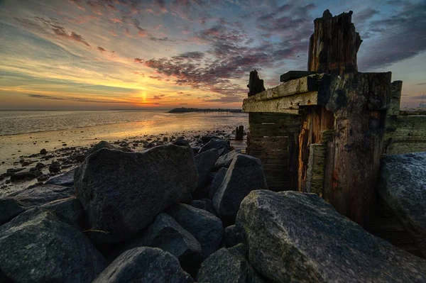 Belo pôr do sol na praia coberto de rochas de diferentes formas e tamanhos — Fotografia de Stock