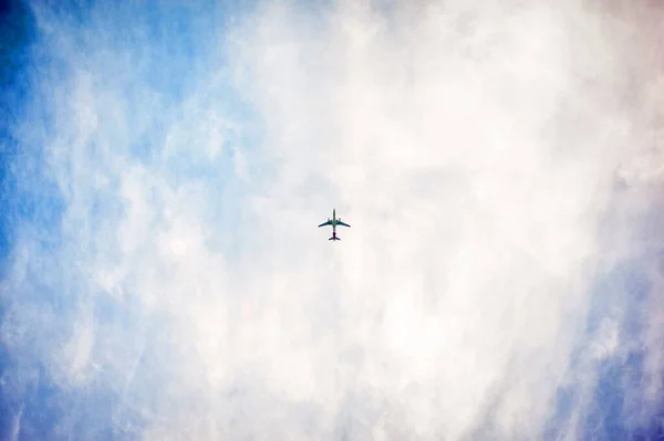 Низький кут зйомки літака, що літає високо в небі з чистими білими хмарами — стокове фото