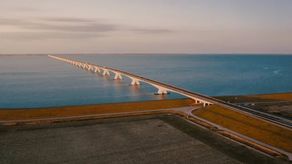 Alto ángulo de disparo de un puente que va al océano bajo el hermoso cielo nublado —  Fotos de Stock
