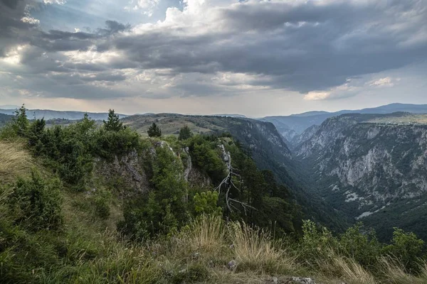 Tiro de tirar o fôlego de um desfiladeiro nas montanhas e o céu escuro nublado no fundo — Fotografia de Stock