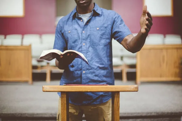Close-up van een mannetje dat de bijbel leest bij een houten statief met een wazige achtergrond — Stockfoto