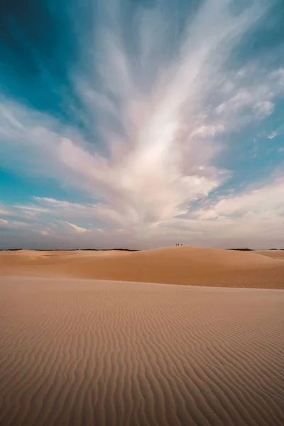 Tiro vertical de las colinas arenosas bajo las hermosas nubes en el cielo — Foto de Stock