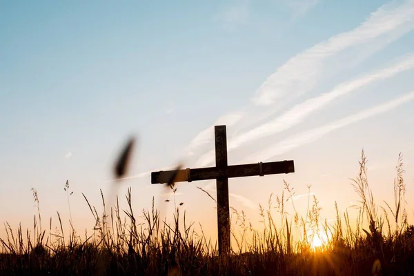 Selective focus shot of a handmade wooden cross in a grassy field under a beautiful sky — Stock Photo, Image