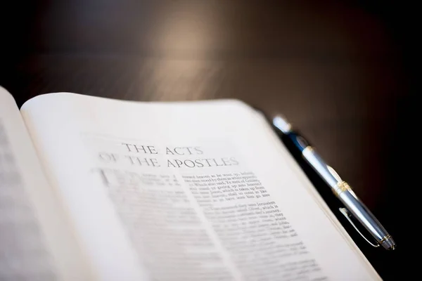 Closeup shot of a pen bible near a fountain pen on a wooden surface with a  blurred background — Stock Photo, Image