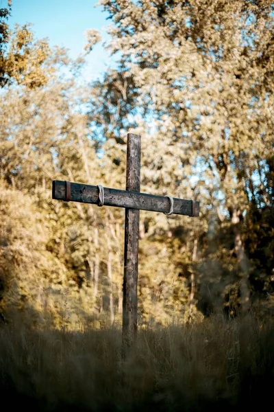Svislý záběr dřevěného kříže na travnatém poli s rozmazaným pozadím — Stock fotografie