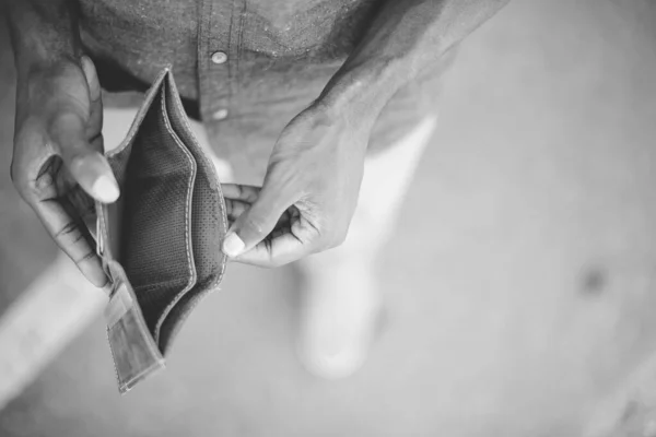 Fotografia aérea em tons de cinza de um homem segurando sua carteira vazia com um fundo embaçado — Fotografia de Stock