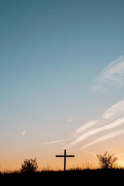 Silhouette di una croce di legno su una collina erbosa con un bel cielo sullo sfondo — Foto Stock