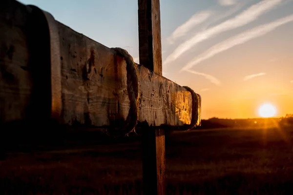 Primer plano de una cruz de madera con el sol brillando en el cielo borroso — Foto de Stock