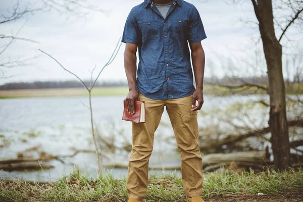 Крупним планом знімок чоловіка, який тримає Біблію, стоячи з розмитим тлом — стокове фото